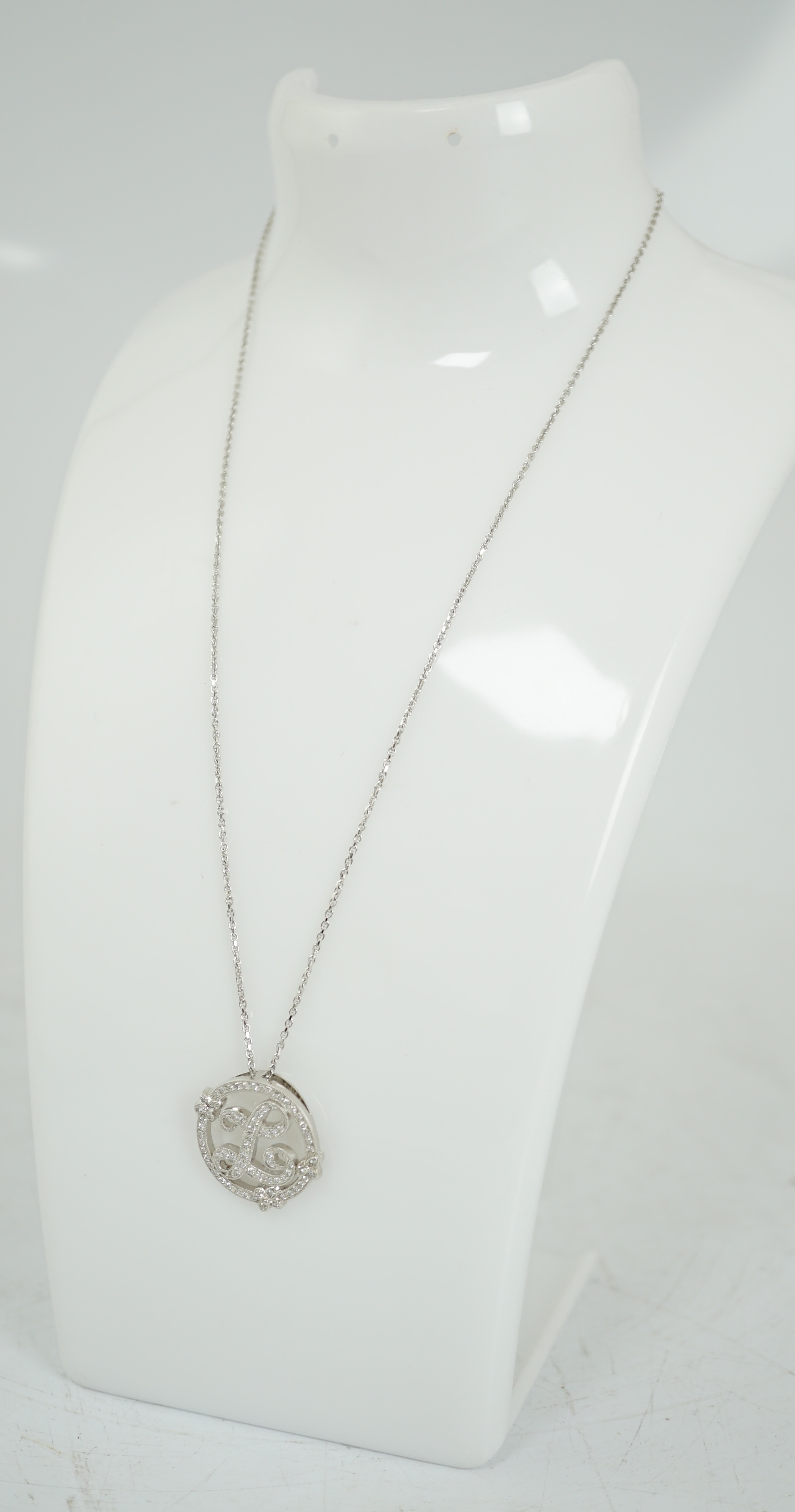 A modern 18k white gold and diamond chip cluster set circular initial 'L' pendant, on an 18k white gold necklace